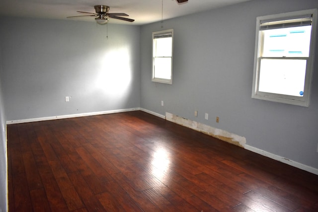 empty room with hardwood / wood-style flooring, a ceiling fan, and baseboards