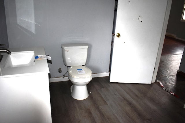 bathroom with baseboards, wood finished floors, vanity, and toilet