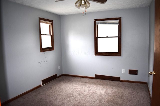 carpeted empty room featuring a wealth of natural light, a ceiling fan, and baseboards