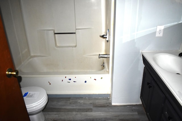 bathroom featuring wood finished floors, toilet, vanity, and bathtub / shower combination