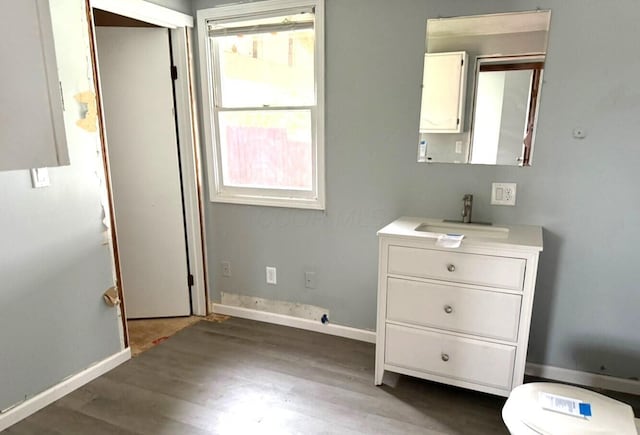 bedroom with baseboards, wood finished floors, and a sink
