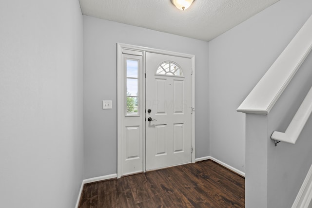 entryway with wood finished floors, baseboards, and a textured ceiling