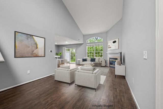 living room with high vaulted ceiling, a tiled fireplace, wood finished floors, and baseboards