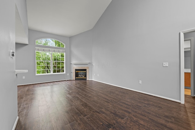 unfurnished living room featuring wood finished floors, a fireplace, baseboards, and vaulted ceiling