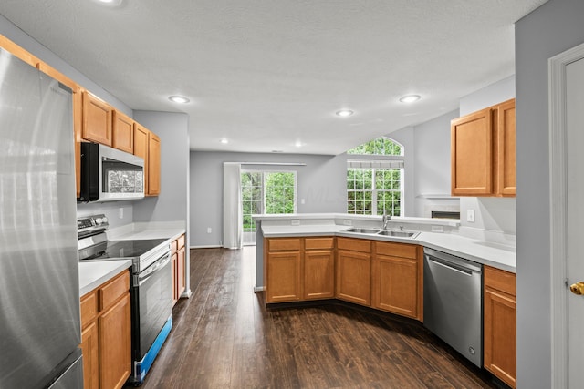 kitchen featuring stainless steel appliances, a peninsula, dark wood-type flooring, light countertops, and recessed lighting