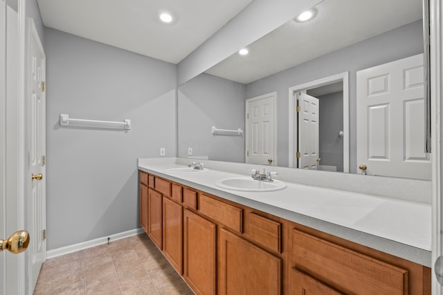 bathroom featuring baseboards, double vanity, recessed lighting, and tile patterned flooring