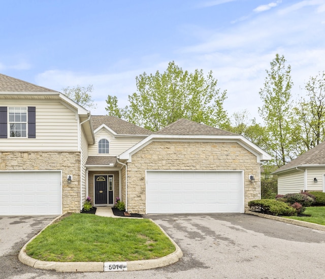 view of front of property with stone siding, asphalt driveway, a front yard, and roof with shingles