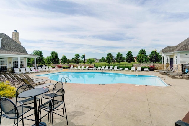 community pool with a patio area and fence