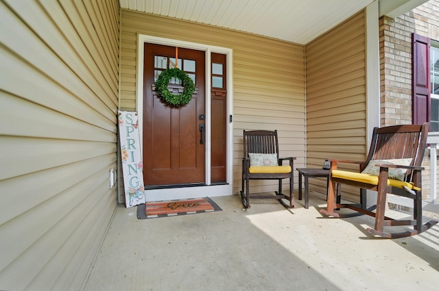 view of exterior entry with a porch and brick siding