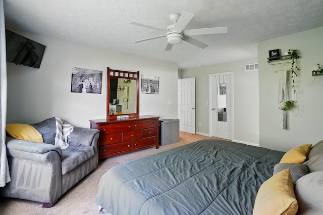 bedroom featuring visible vents, a ceiling fan, a textured ceiling, and light carpet
