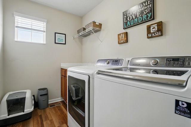 laundry area featuring visible vents, washing machine and clothes dryer, cabinet space, baseboards, and dark wood-style floors