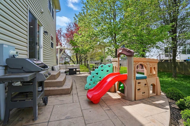 view of playground featuring fence, an outdoor hangout area, and a patio area