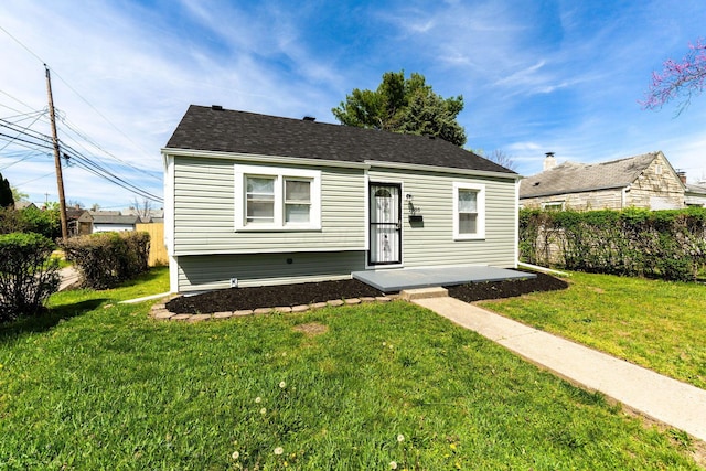 bungalow-style home featuring fence, roof with shingles, and a front yard