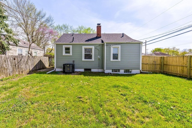 back of house with a chimney, central AC, a fenced backyard, and a lawn