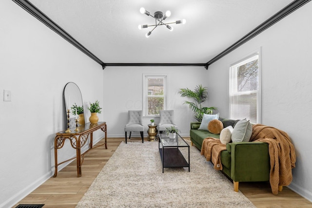 living area featuring an inviting chandelier, light wood-style floors, and ornamental molding