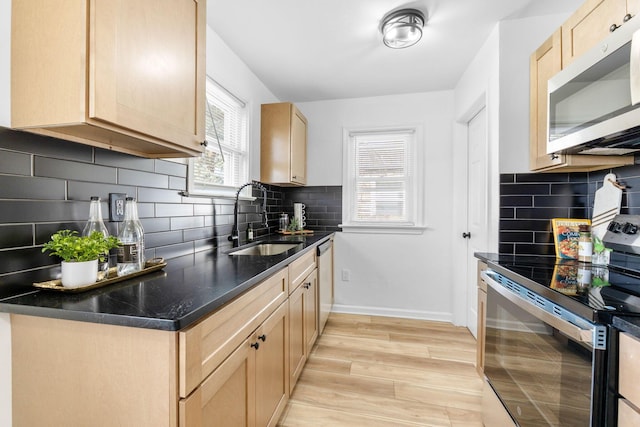 kitchen with decorative backsplash, light brown cabinetry, a sink, and appliances with stainless steel finishes