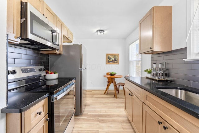 kitchen with backsplash, light wood-style floors, light brown cabinets, and stainless steel appliances