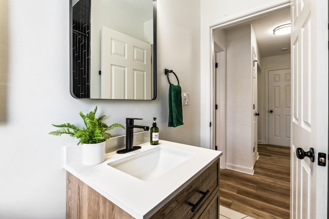 bathroom featuring baseboards, wood finished floors, and vanity