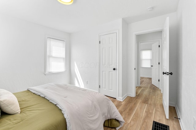 bedroom with visible vents, light wood finished floors, baseboards, and multiple windows