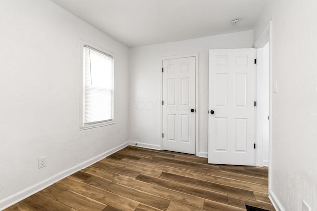 unfurnished bedroom featuring baseboards and dark wood-style flooring