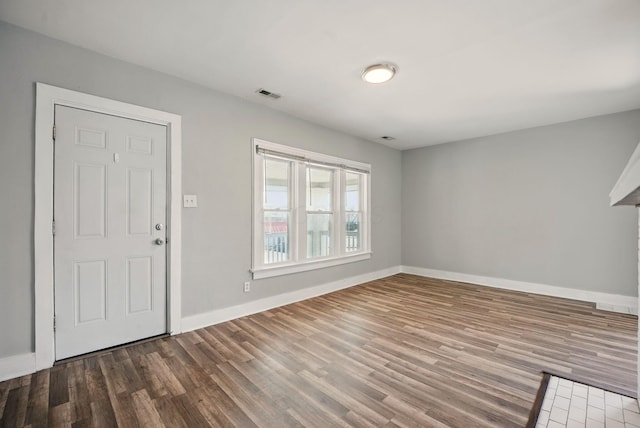 foyer entrance featuring visible vents, wood finished floors, and baseboards