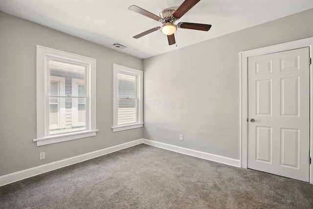 empty room with baseboards, a ceiling fan, dark colored carpet, and visible vents