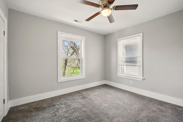 carpeted spare room with baseboards, a ceiling fan, and visible vents
