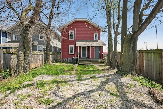 back of house with a fenced backyard and central AC unit