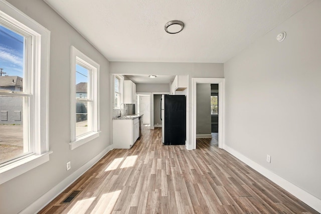 unfurnished living room featuring light wood-style floors, visible vents, and baseboards