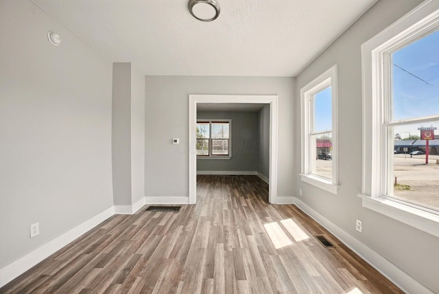 spare room with baseboards and wood finished floors