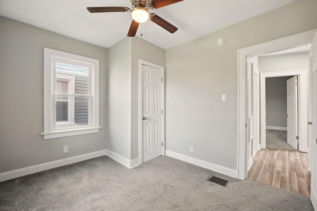 unfurnished bedroom featuring baseboards, visible vents, carpet flooring, and ceiling fan