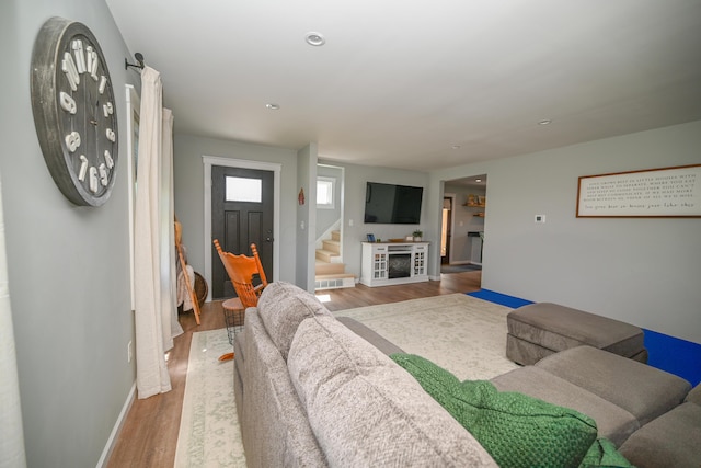 living area featuring wood finished floors, baseboards, recessed lighting, and stairs