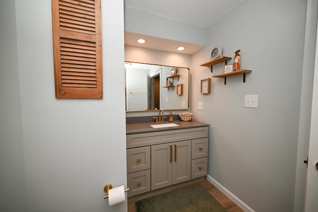 bathroom with recessed lighting, wood finished floors, vanity, and baseboards