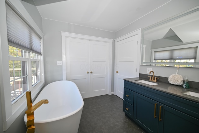 full bathroom featuring tile patterned flooring, double vanity, a sink, and a freestanding bath