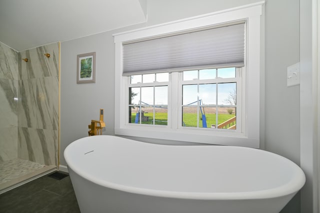 full bathroom featuring a freestanding tub, tiled shower, and tile patterned flooring