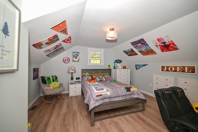 bedroom featuring visible vents, light wood-style flooring, lofted ceiling, and baseboards