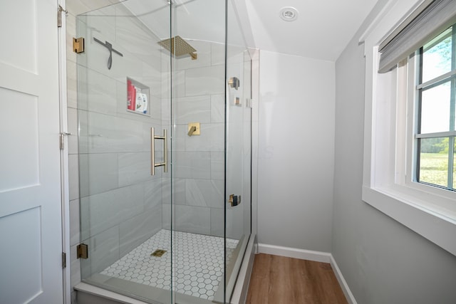 full bath featuring a stall shower, a wealth of natural light, and wood finished floors