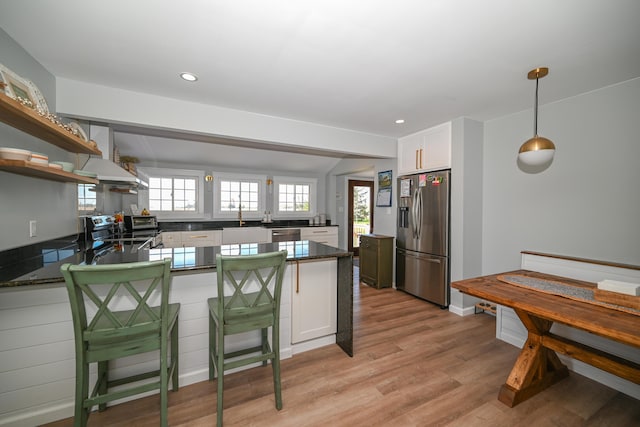 kitchen featuring a sink, custom range hood, light wood-style flooring, a peninsula, and appliances with stainless steel finishes