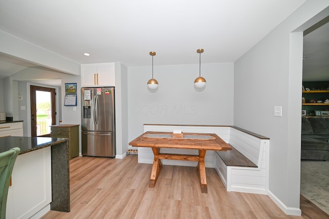 kitchen with baseboards, light wood-type flooring, stainless steel refrigerator with ice dispenser, and pendant lighting