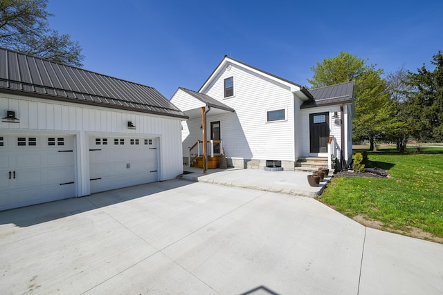view of front of home featuring driveway, metal roof, a front yard, and an outbuilding