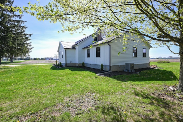 view of property exterior with central air condition unit and a lawn