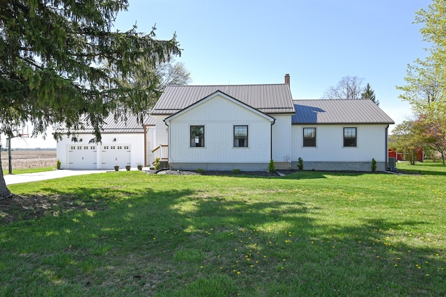 view of front of house featuring a chimney, metal roof, a garage, driveway, and a front yard