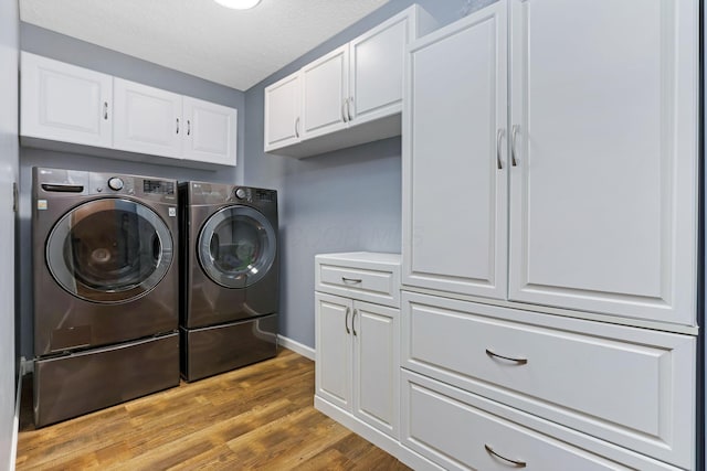 1616 Saddlebrook Dr, Heath, OH 43056 - laundry room with baseboards, light wood-type flooring, a textured ceiling, cabinet space, and independent washer and dryer