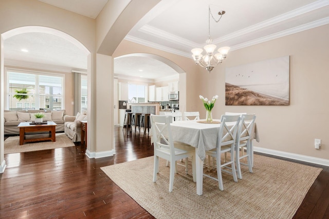 dining area featuring a chandelier, crown molding, dark wood-style floors, and arched walkways