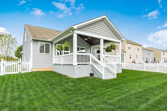 back of property featuring a shingled roof, ceiling fan, stairway, a yard, and a fenced backyard