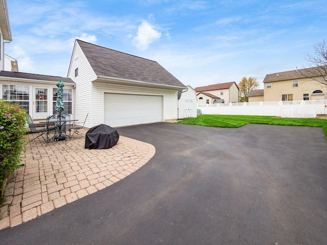 view of home's exterior with driveway, roof with shingles, a lawn, fence, and a garage