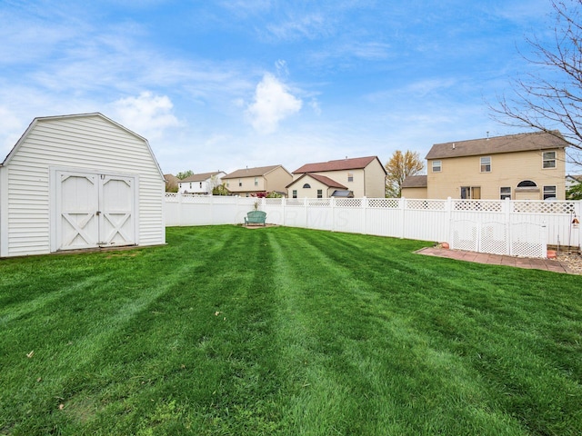 view of yard featuring a storage shed, a residential view, an outdoor structure, and a fenced backyard