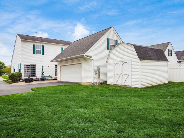 view of side of home with roof with shingles, aphalt driveway, an attached garage, and a lawn