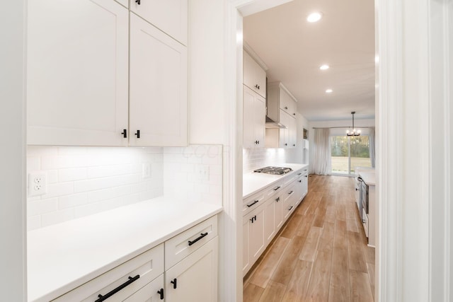 kitchen with recessed lighting, stainless steel gas stovetop, light countertops, white cabinets, and backsplash