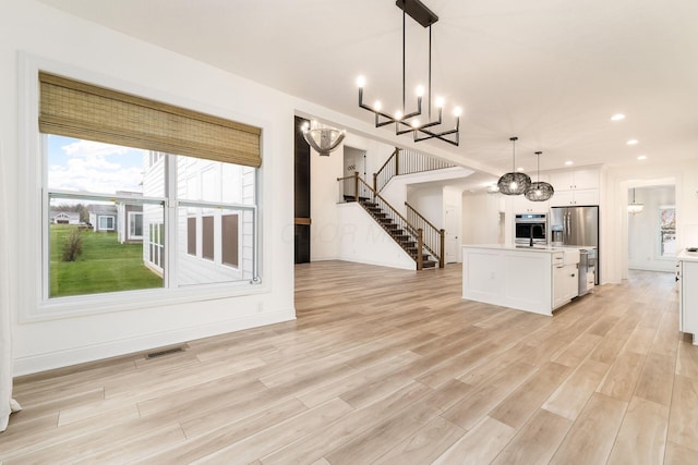 unfurnished living room with recessed lighting, stairs, a chandelier, light wood finished floors, and visible vents
